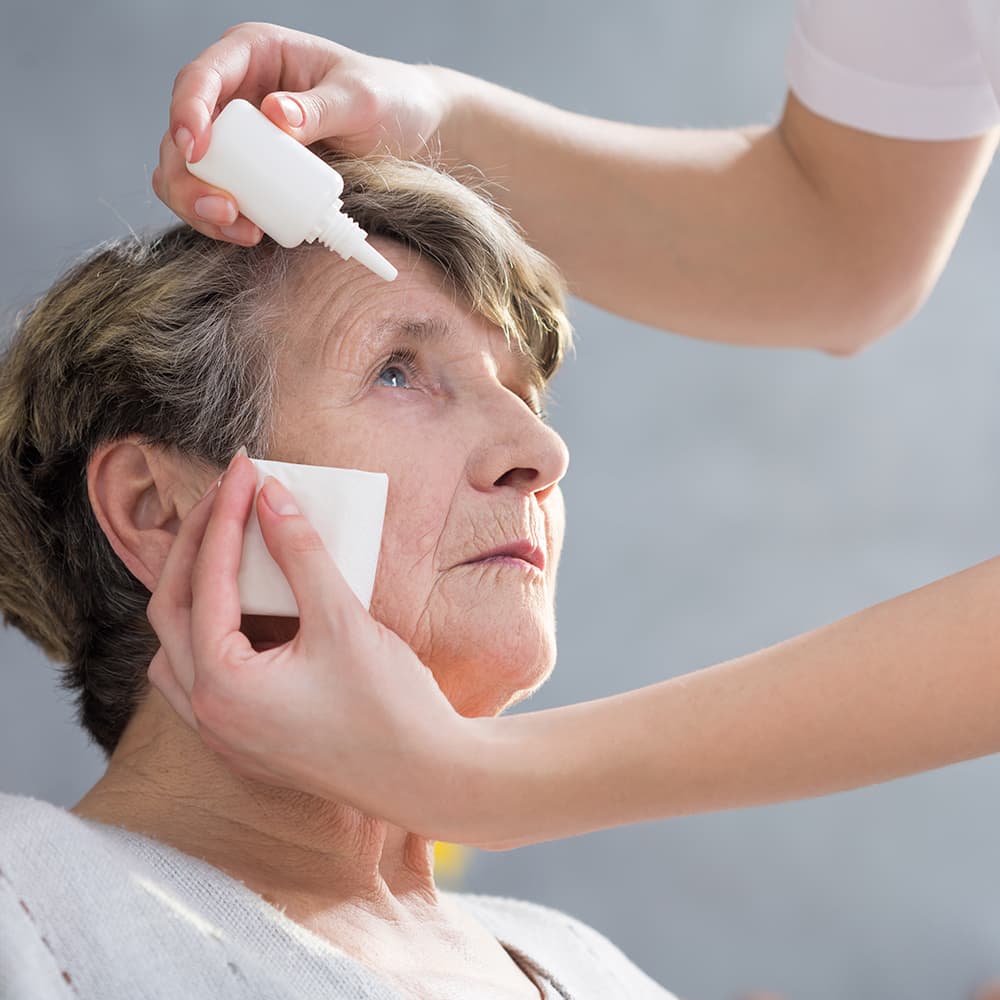 Senior woman receiving eye drops