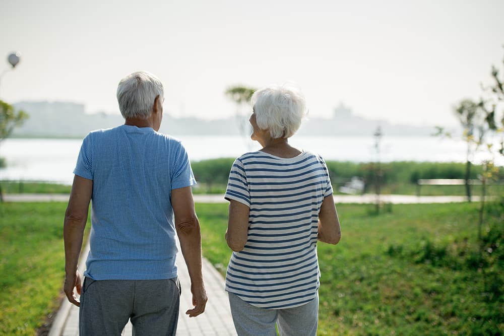 A senior couple walking outside towards the beach
