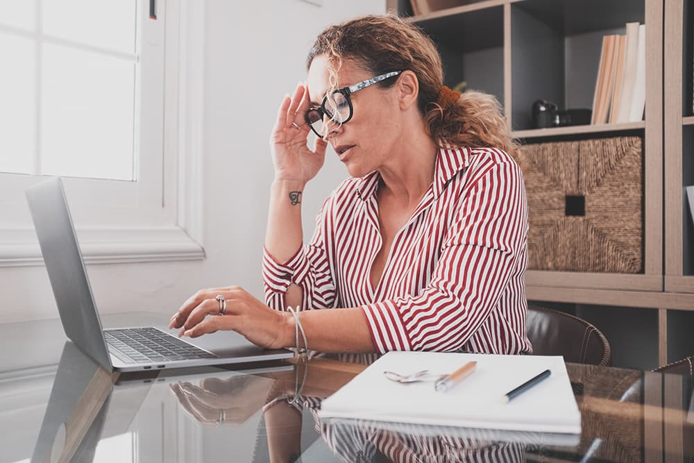 A woman working on her laptop and suffering from dry eyes