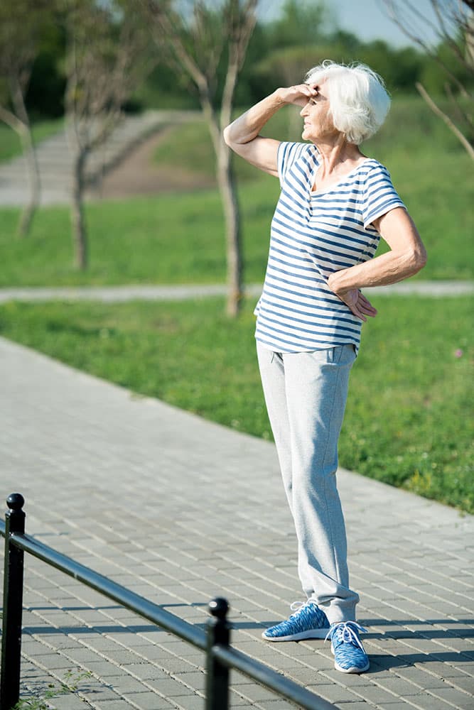 An older woman standing outside on a sunny day