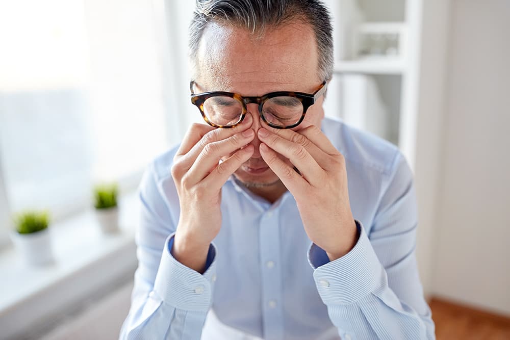 Business man in glasses rubbing his eyes