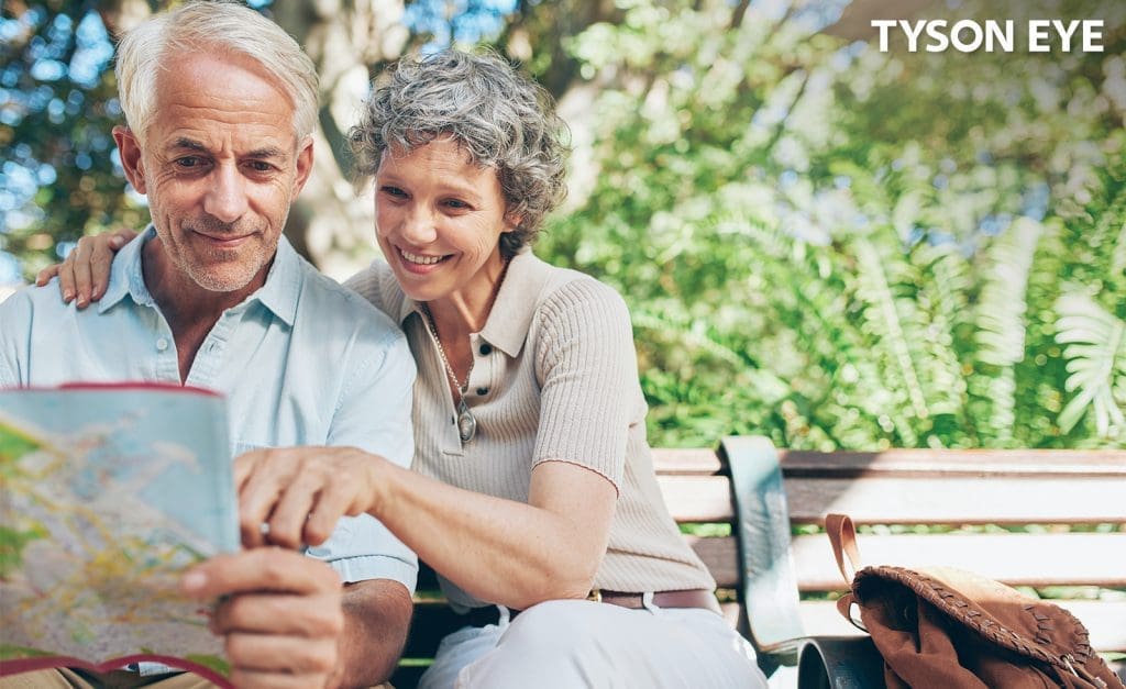 A couple sitting outside reading a map and showing the benefits of laser cataract surgery