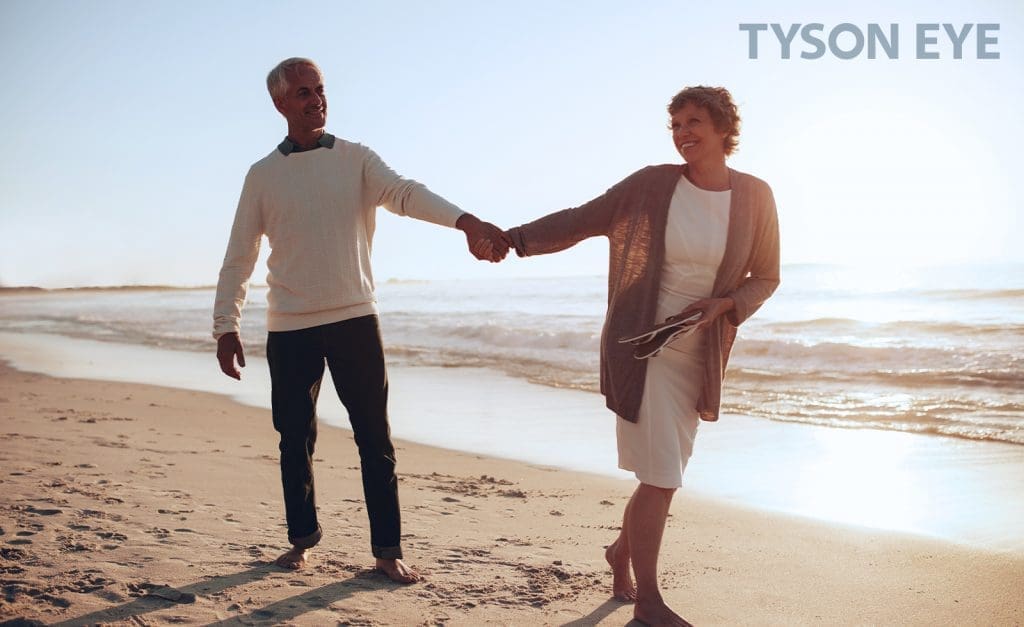 a couple smiling on the beach and showing how to keep your eyes healthy during the winter