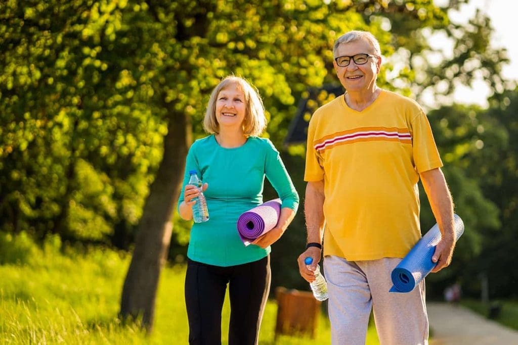 Two senior people walking with yoga mats